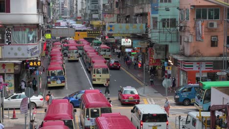 Chinesische-Fußgänger-Und-Pendler-überqueren-Eine-Hektische-Straße,-Während-Zahlreiche-Minibusse-Im-Bezirk-Mong-Kok,-Hongkong,-In-Einer-Schlange-Stationiert-Sind