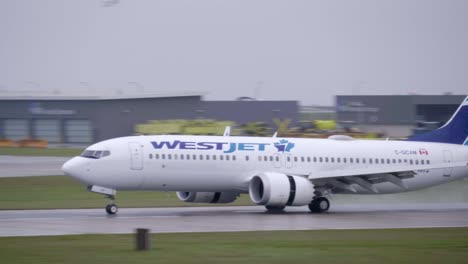 Eine-Westjet-Boeing-737-Max-Landet-Auf-Einer-Nassen-Landebahn-Und-Verfolgt-Die-Ansicht