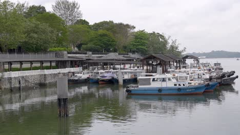 Distant-View-Of-Passengers-Walking-Towards-Bumboats-Moored-At-Changi-Village-Jetty-In-Singapore