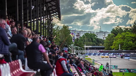 Static-shot-of-sports-spectators-sitting-in-an-open-stadium-to-watch-RX-World-Rally-Cross-Championship-in-Riga,-Latvia-on-a-cloudy-day