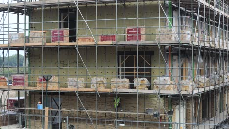 Timelapse-of-brick-layers-on-half-scaffolding-level-at-construction-site-with-indication-for-bee-homes-in-the-side