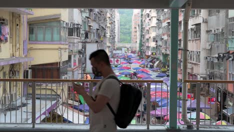 Im-Hintergrund-In-Hongkong-Ist-Eine-Szene-Des-Täglichen-Lebens-Chinesischer-Fußgänger-Zu-Sehen,-Die-Durch-Eine-Fußgängerbrücke-Gehen,-Während-Ein-Straßenmarkt-Im-Freien-Stattfindet