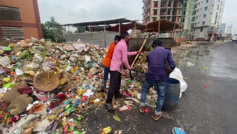 Workers-Emptying-Rubbish-Cart-At-Refuse-Site-Beside-Road-In-Dhaka,-Bangladesh