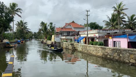 Canoes-Sailing-Through-Kumarakom-Residential-Area-Via-Canal-In-Kerala,-India