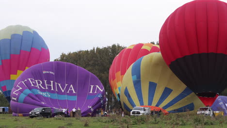 Groups-of-people-inflating-hot-air-balloons,-preparing-for-launch