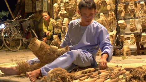 Vietnamese-man-carving-wooden-faces-out-of-bamboo-root-on-street-in-Hoi-An