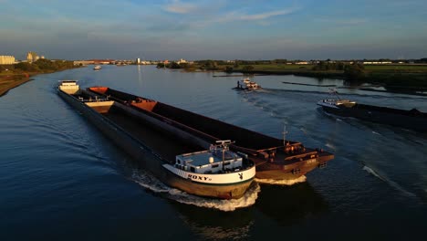 Aerial-View-Of-Forward-Bow-Of-Empty-KVB-Roxy-Cargo-Barge-Navigating-Along-Oude-Maas-With-Evening-Sunlight-Passing-Another-Ship