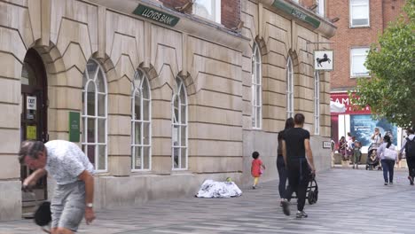 Chelmsford-city-center-with-Lloyds-bank,-a-homeless-person-and-shopper-walking-by