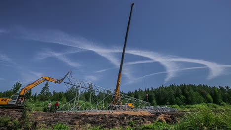 Time-Lapse-of-Construction-Workers-and-Cranes-Raising-Up-Electricity-Tower-in-Countryside-Landscape-WIth-Strange-Circular-Clouds-in-the-Sky