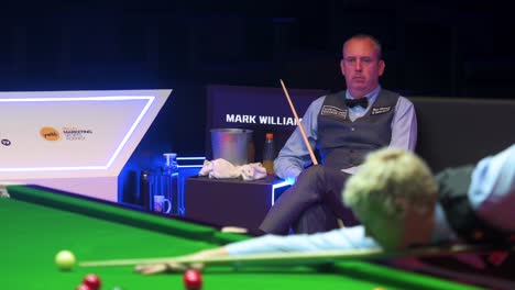 A-professional-snooker-player,-Welsh-Mark-Williams,-looks-on-as-Australian-player-Neil-Robertson-plays-a-shot-during-the-Hong-Kong-master-tournament-competition-event