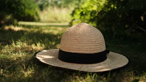 Summer-straw-hat-placed-on-the-grass-under-shadow-of-tree