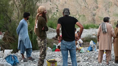 Rückansicht-Von-Zwei-Männern,-Die-Miteinander-Reden-Und-Neben-Anderen-Männern-Stehen,-Während-Sie-Auf-Dem-Felsigen-Und-Zerklüfteten-Gelände-In-Balochistan,-Pakistan,-Stehen