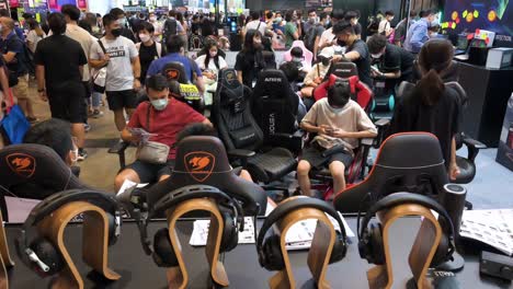 Chinese-visitors-and-retail-tech-buyers-browse,-test,-and-buy-gaming-chairs-during-a-Computer-and-Communications-Festival-as-shoppers-look-for-discounted-electronics-and-accessories-branded-products