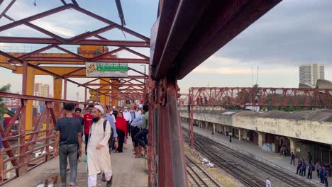 People-walking-at-foot-over-bridge-of-Kamalapur-railway-station,-Dhaka---Static-shot