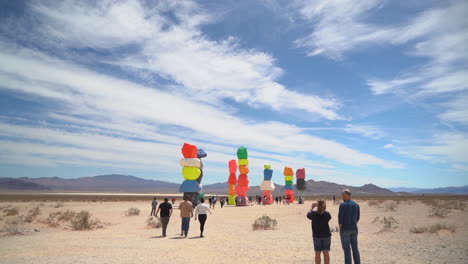 People-in-Front-of-Seven-Magic-Mountains-Colorful-Art-Installation-in-Nevada-Desert,-Slow-Motion