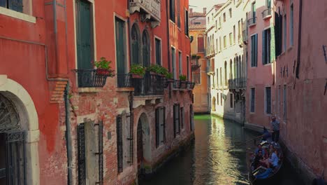 Ein-Kanal-In-Venedig,-Italien-Mit-Einem-Gondelboot,-Gondoliere-Und-Touristen,-Alten-Häusern-Und-Einer-Domkirche-In-Der-Nähe-Von-San-Marco-Und-Der-Rialtobrücke