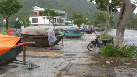 Man-in-Raincoat-Tying-The-Boat-on-Heavy-Rain,-Preparation-For-Incoming-Tropical-Storm,-Da-Nang,-Vietnam