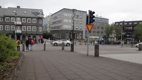 Downtown-Reykjavik,-Iceland-with-cars-moving-on-street-and-people-walking-with-stable-video