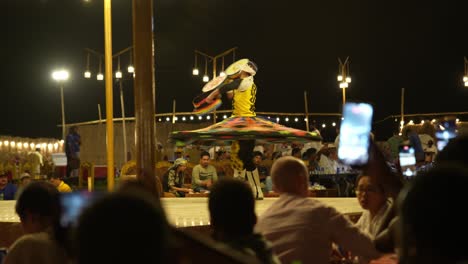 Local-man-performs-traditional-folk-dance-at-night-as-part-of-a-desert-safari-show,-Dubai