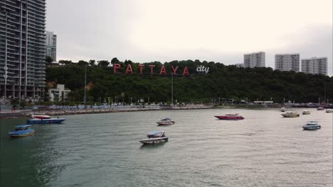 Luftaufnahme-Der-Stadt-Pattaya-Mit-Booten-Im-Vordergrund-Und-Schriftart-Im-Hintergrund