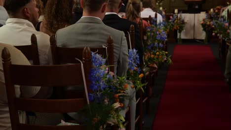 Wedding-Ceremony-With-Guests-Seated-On-Decorated-Wooden-Chair-Inside-The-Chapel