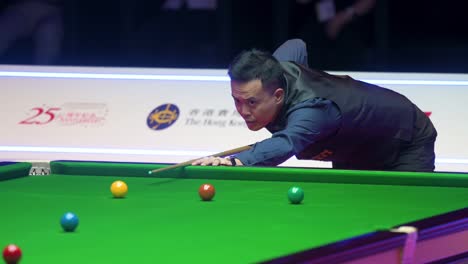 Marco-Fu,-a-professional-snooker-player-from-Hong-Kong,-plays-a-shot-as-he-strikes-a-ball-during-the-final-match-of-the-Hong-Kong-Masters-snooker-tournament-event