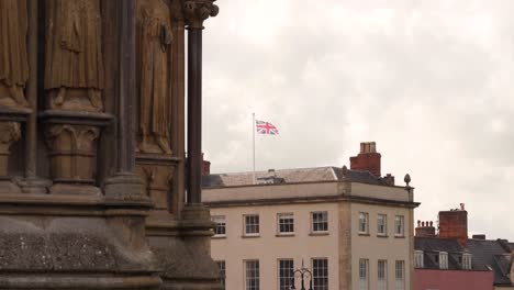 Union-Jack-flag-shaking-in-the-wing-in-the-background-of-one-of-the-towers-of-the-Wells-Cathedral,-steady-camera,-4K