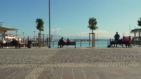 Tourists-sitting-by-the-lake-on-a-bench-relaxing-in-a-sunny-day-in-Italy
