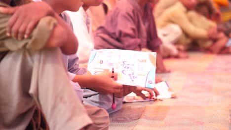 Video-Der-Zahlreichen-Schüler,-Die-Mit-Büchern-Im-Arm-In-Der-Schule-Im-Ländlichen-Pakistan-Auf-Der-Matte-Sitzen