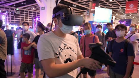 Ein-Chinesischer-Gamer-Spielt-Ein-Virtual-Reality-Multiplayer-Shooting-Videospiel,-Während-Besucher-Ihm-Beim-Computer--Und-Kommunikationsfestival-In-Hongkong-Beim-Spielen-Zusehen