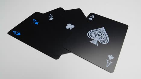 Orbit-shot-of-the-four-aces-on-a-white-surface-of-a-deck-of-black-cards
