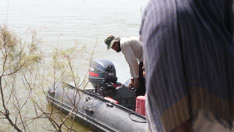 Pakistani-Male-Checking-Inflatable-Boat-Motor-Engine-In-Sindh,-Pakistan