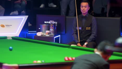 Professional-snooker-player-of-Hong-Kong,-Marco-Fu,-rests-and-looks-at-a-play-between-sets-during-the-final-match-of-the-Hong-Kong-Masters-snooker-tournament-event