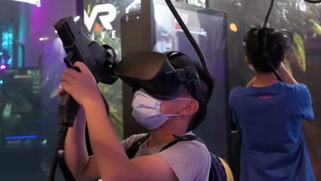 Chinesische-Junge-Gamer-Spielen-Ein-Virtual-reality-shooting-videospiel,-Während-Sie-Während-Des-Computer--Und-Kommunikationsfestivals-In-Hong-Kong-Nachladen,-Zielen-Und-Auf-Ziele-Schießen