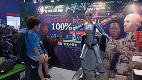 Ein-Vater-Und-Sein-Sohn-Begrüßen-Und-Interagieren-Mit-Einem-Automatisierten-Humanoiden-Roboter-Mit-Künstlicher-Intelligenz,-Der-Während-Des-Computer--Und-Kommunikationsfestivals-In-Hongkong-Ausgestellt-Wurde