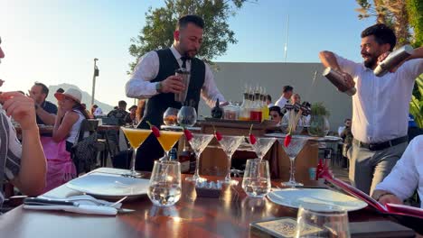 Tableside-service-staff-mixing-fresh-cocktails-at-Nusret-Salt-Bae-restaurant-in-Yalikavak-port,-luxury-dining-experience-at-a-famous-restaurant-in-Bodrum-Turkey,-4K-shot