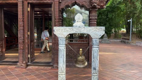 Bronze-bell-ringing-and-swinging-outside-the-main-entrance-of-three-story-high-heritage-building-nepalese-pagoda,-Parklands,-South-Bank-Brisbane-city