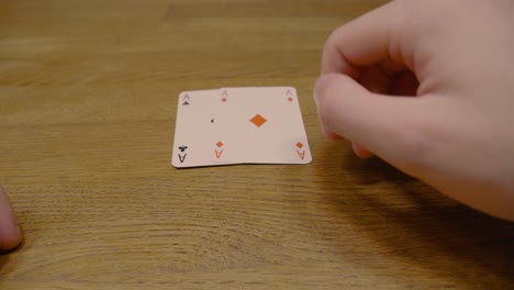 Panning-shot-of-a-poker-player-holding-two-ace-of-spades-cards-during-a-Texas-hold-em-game-on-a-high-quality-wooden-table