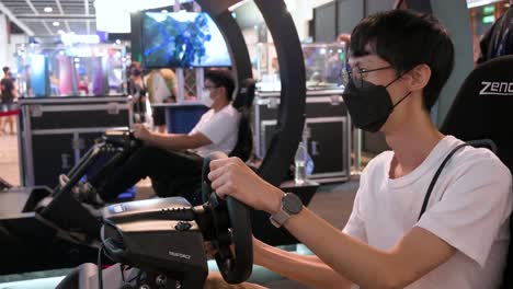 Chinesische-Gamer-Spielen-Ein-Themenorientiertes-Rennvideospiel,-Während-Besucher-Das-Hong-Kong-Computer-And-Communication-Festival-In-Hong-Kong-Besuchen