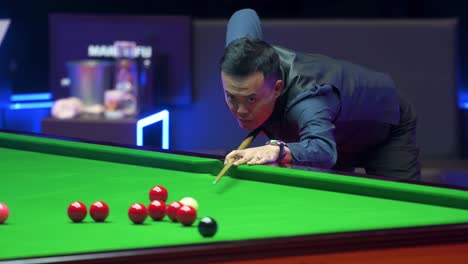 Marco-Fu,-a-professional-snooker-player-from-Hong-Kong,-plays-a-shot-as-he-hits-a-ball-during-the-final-match-of-the-Hong-Kong-Masters-snooker-tournament-event