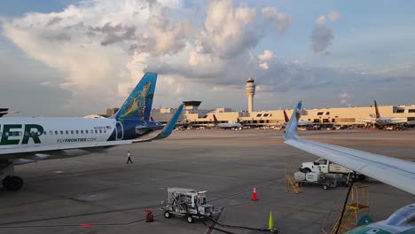 Aerolíneas-Fronterizas-Airbus-A320-En-La-Puerta-Del-Aeropuerto-De-Atlanta-Con-Recorrido-Realizado-Por-Piloto-Con-Aviones-Delta-Y-Torre-Atc-En-Segundo-Plano.