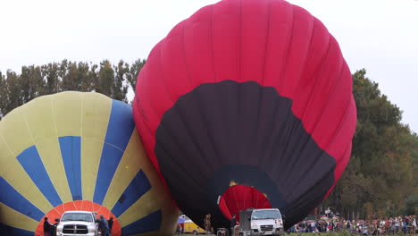 Crowd-of-people-watching-hot-air-balloons-being-inflated-for-takeoff