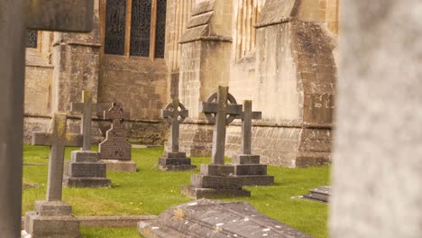 Wells-Cathedral-outside-cemetery,-camera-rotating-to-the-left-showing-some-of-the-grave-and-the-grave-stones-and-crosses