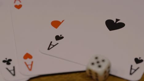 Slow-dolly-in-shot-of-poker-cards-with-ace-of-spades-in-red-and-black-with-dice-on-a-wooden-table