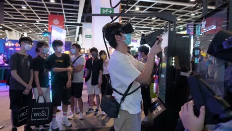 Jóvenes-Jugadores-Chinos-Juegan-Videojuegos-De-Disparos-De-Realidad-Virtual-Mientras-Otros-Visitantes-Hacen-Cola-Y-Esperan-Su-Turno-Para-Jugar-Durante-El-Festival-De-Computadoras-Y-Comunicaciones-De-Hong-Kong-En-Hong-Kong