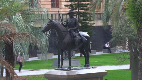 Close-up-shot-of-the-Scout-sculpture,-South-African-War-Memorial-at-Anzac-square-with-office-workers-walking-towards-central-station-during-off-work-period,-downtown-Brisbane-city,-Queensland