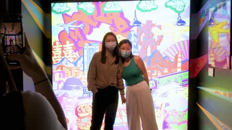 Chinese-visitors-pose-in-front-of-a-digital-art-artwork-at-the-Digital-Art-Fair-showcasing-upcoming-trends-such-as-Web-3