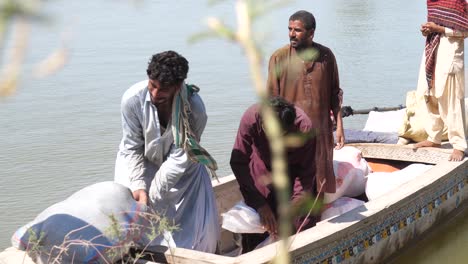 Einheimische-Helfen-Beim-Verladen-Von-Hilfssäcken-Auf-Ein-Boot-Neben-Dem-Fluss-In-Sindh-Für-Die-Fluthilfe-In-Maher-In-Sindh