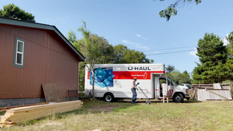 Two-guys-unpack-a-U-Haul-truck-parked-by-a-house