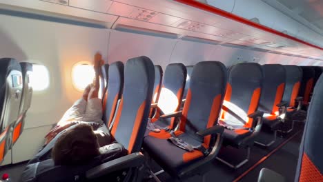 A-person-sleeping,-chilling-relaxing-and-laying-down-on-Easyjet-airplane-seats-at-an-international-airport-in-Malaga-Spain,-Easyjet-flying-experience,-people-going-on-a-holiday,-4K-shot